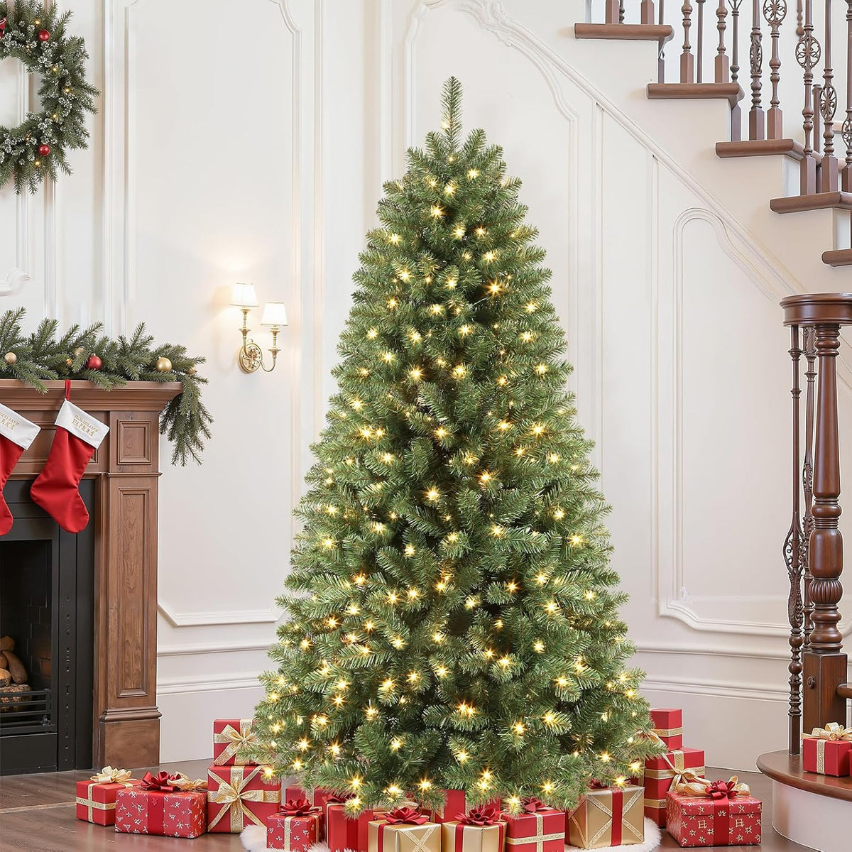 Green spruce Christmas tree in warm-white lighting mode near a staircase and wrapped gifts.