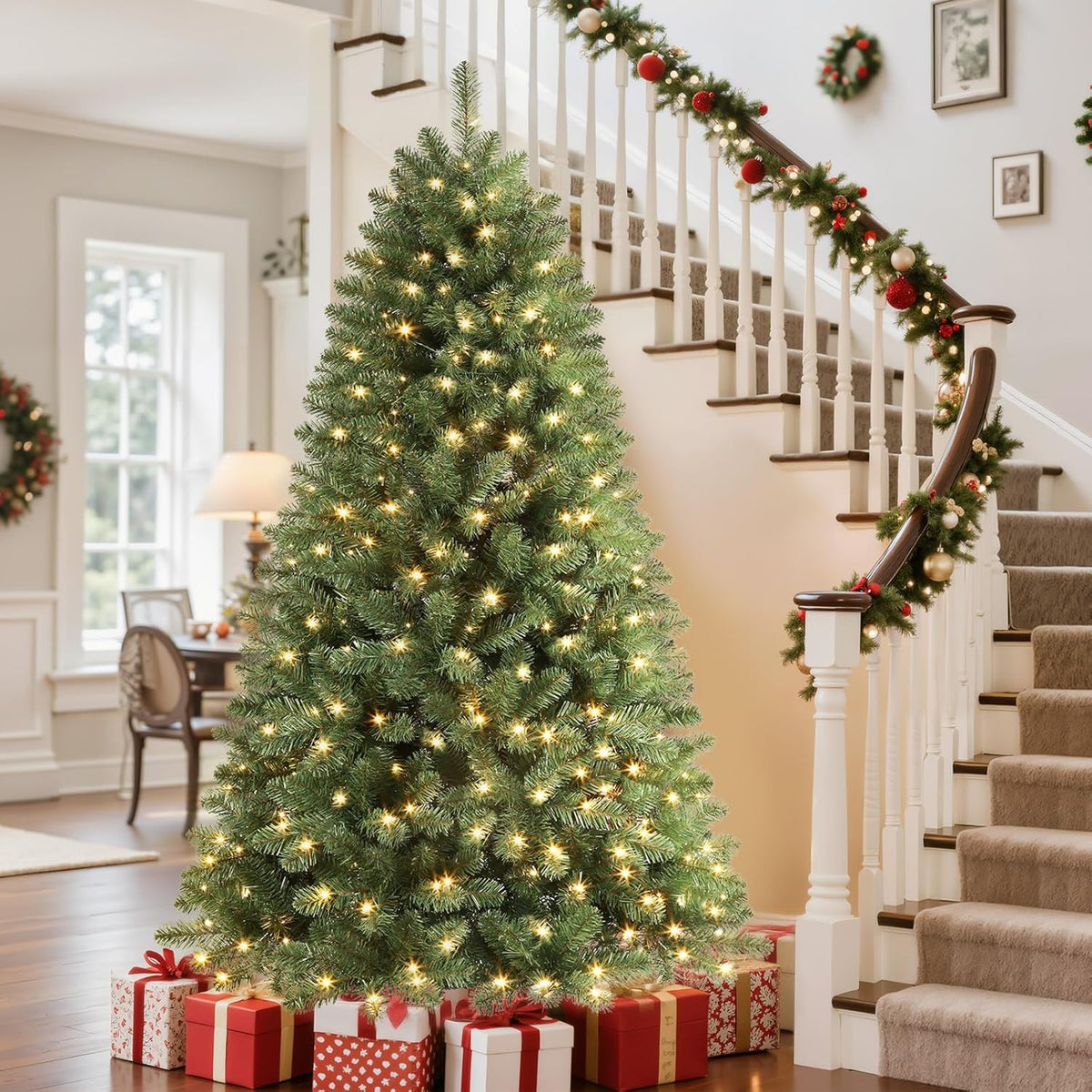 Lit green classic spruce Christmas tree beside a staircase decorated with garland.