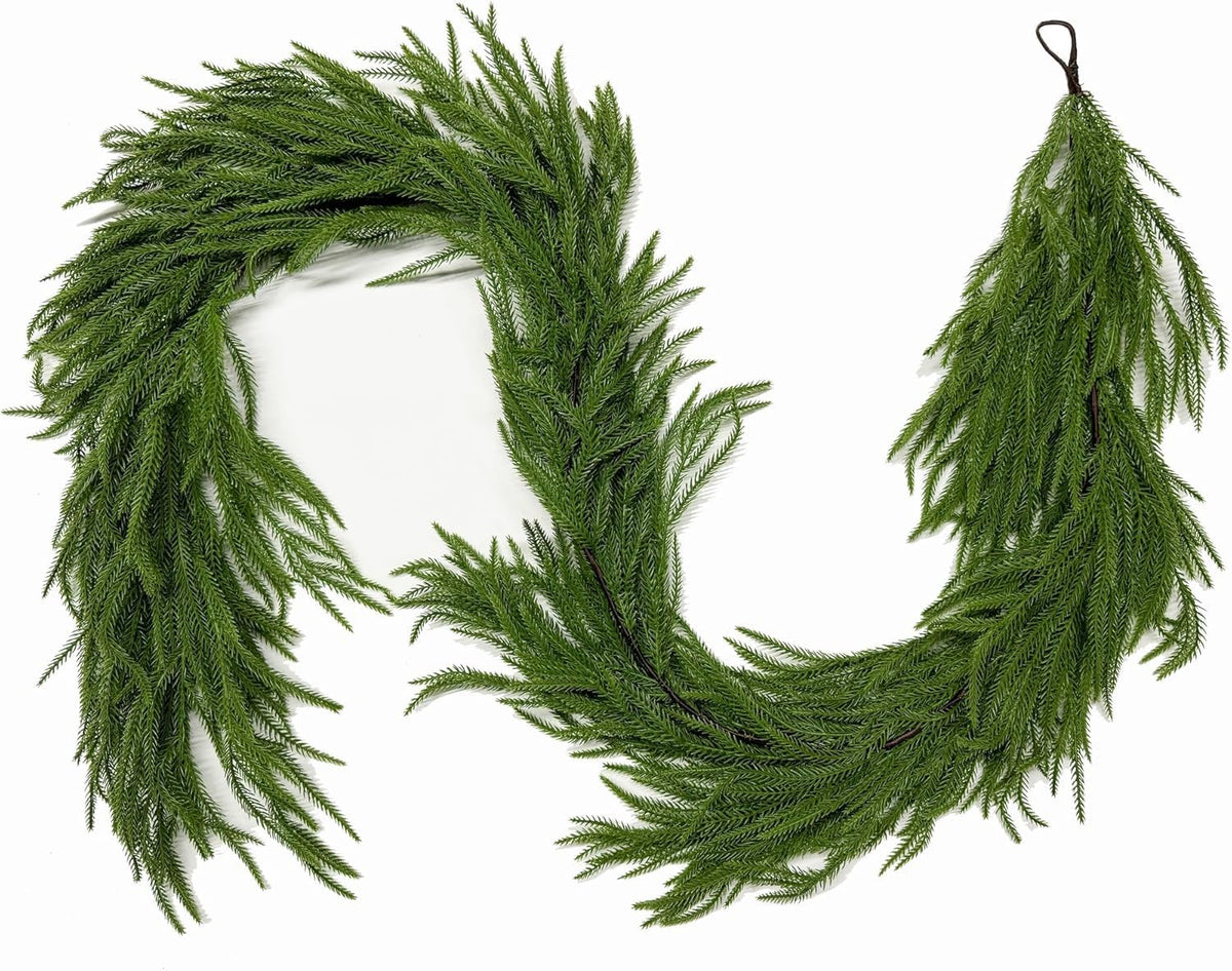 Green artificial Norfolk pine garland arranged in a curved shape on a white background.