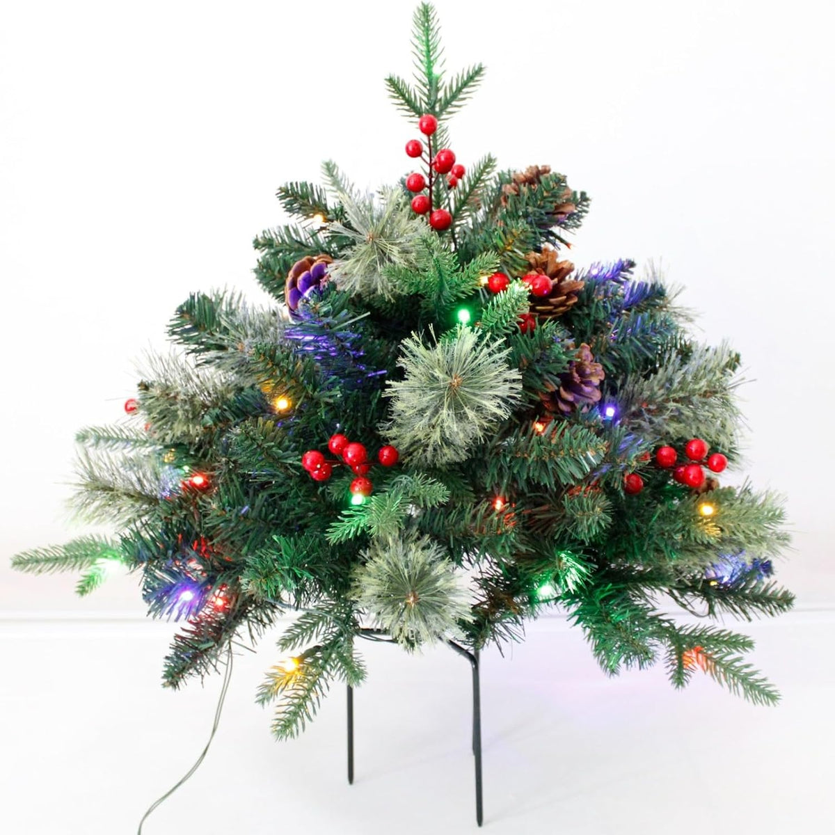 Artificial Christmas urn filler with green foliage, red berry decorations, colored lights and stakes.